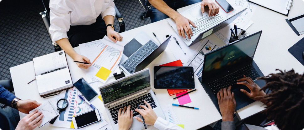 Team collaborating at a desk with laptops and notes during creative event production planning