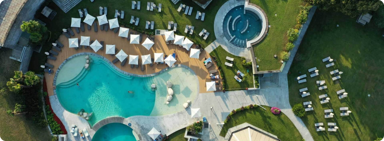 Aerial view of luxury Spanish resort pool deck with cabanas and gardens