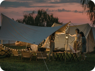 Person under festival tent overlooking lake at sunset