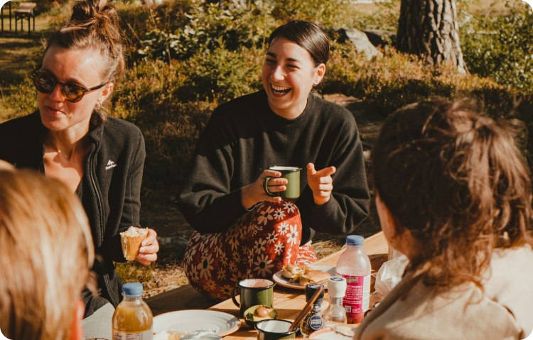 Group laughing at outdoor picnic table during corporate retreat