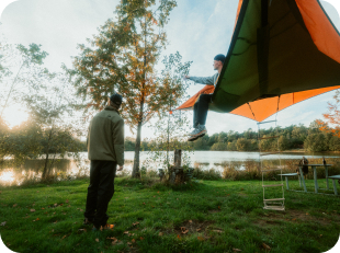 Person standing at edge of forest lake at golden hour